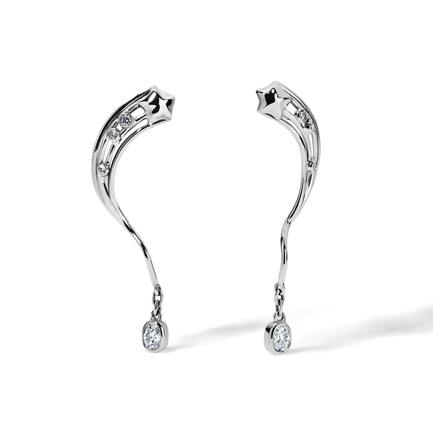A pair of 14 karat white gold with an oval cushion cut diamond dangling earrings. Three small diamonds are set on the rays of a star coming from the top and these rays are connecting to a dangling diamond.