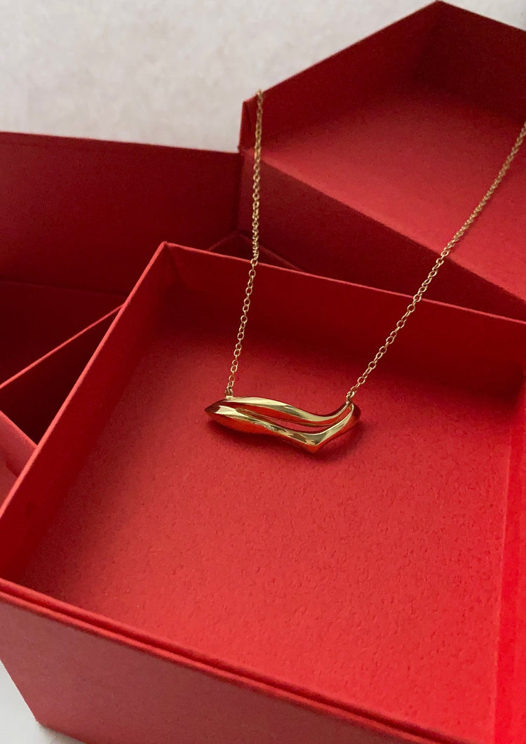 Gold mouth shaped necklace with a cable chain on a red box